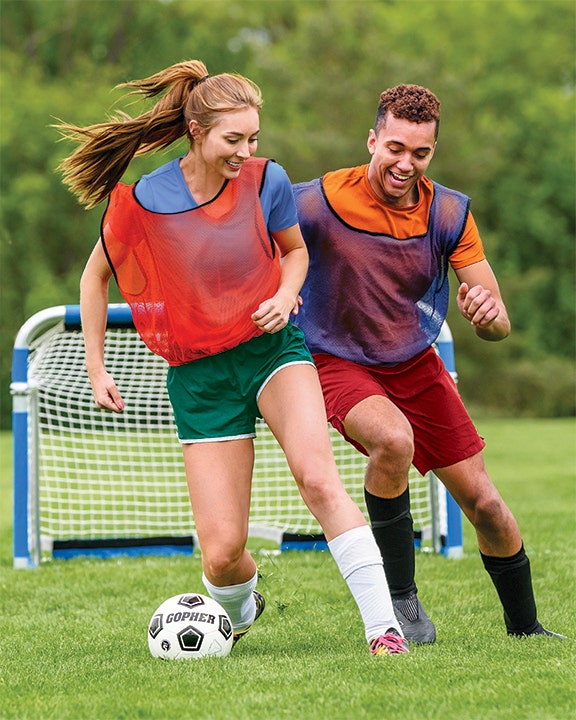 Two students chasing after a soccer ball.