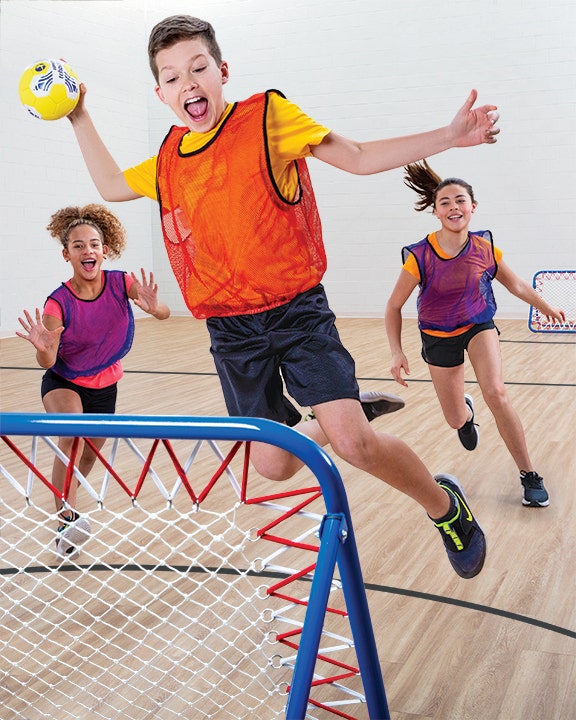 Boy jumping to throw tchoukball at rebounder.